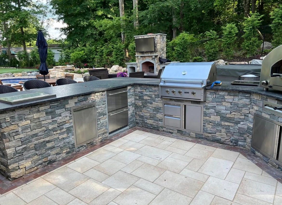 Stone-finished outdoor kitchen with grill and pizza oven