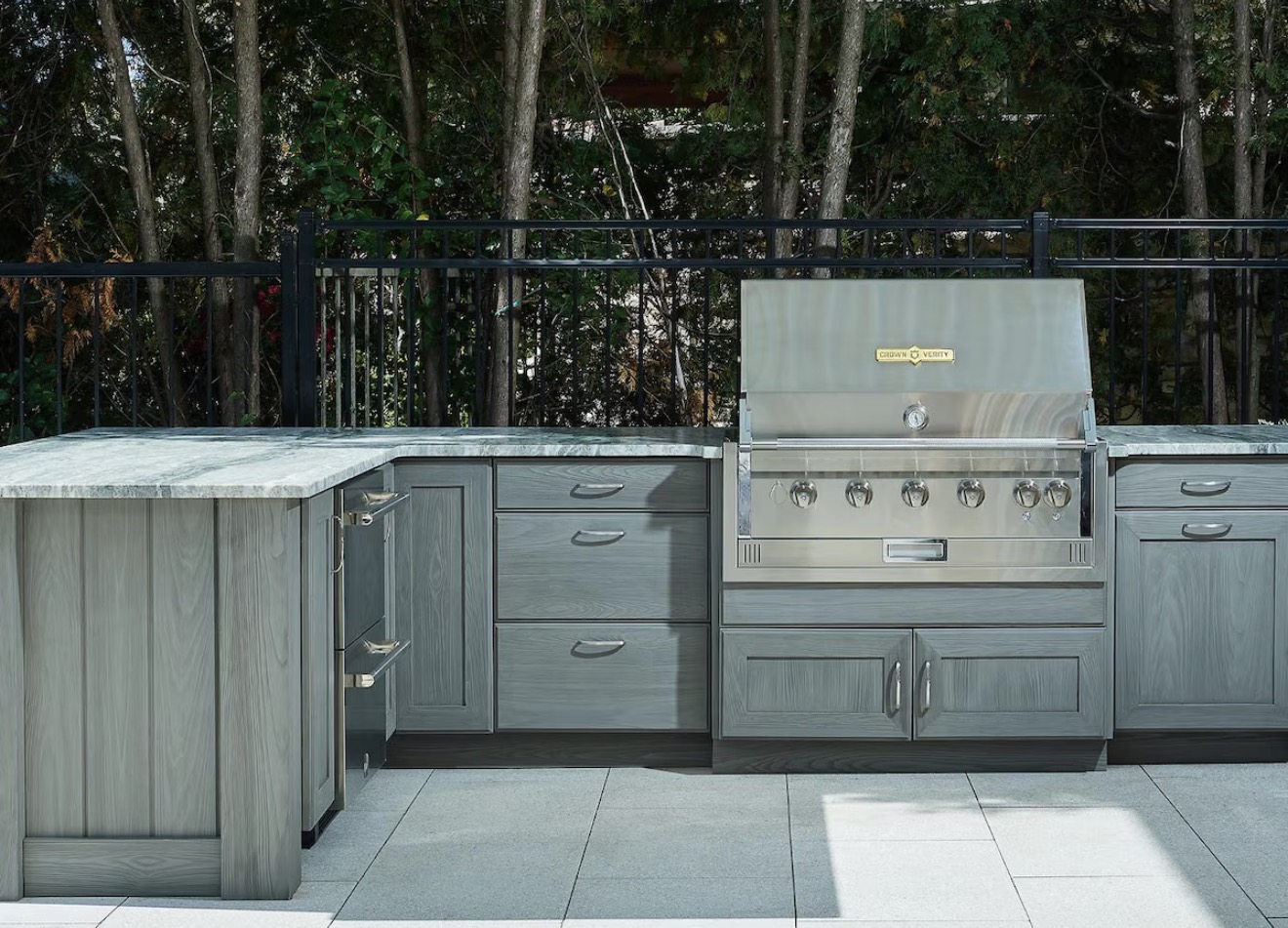 Modular outdoor kitchen with gray woodgrain cabinetry and stainless steel grill